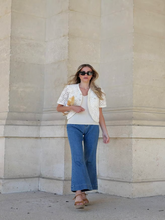 A woman wears openwork jacket and jeans